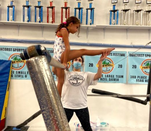 coach teaching child gymnastics